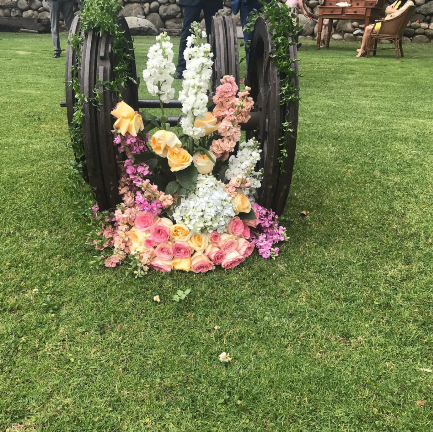 Arreglo floral con rosas y flores blancas sobre carreta de madera para evento
